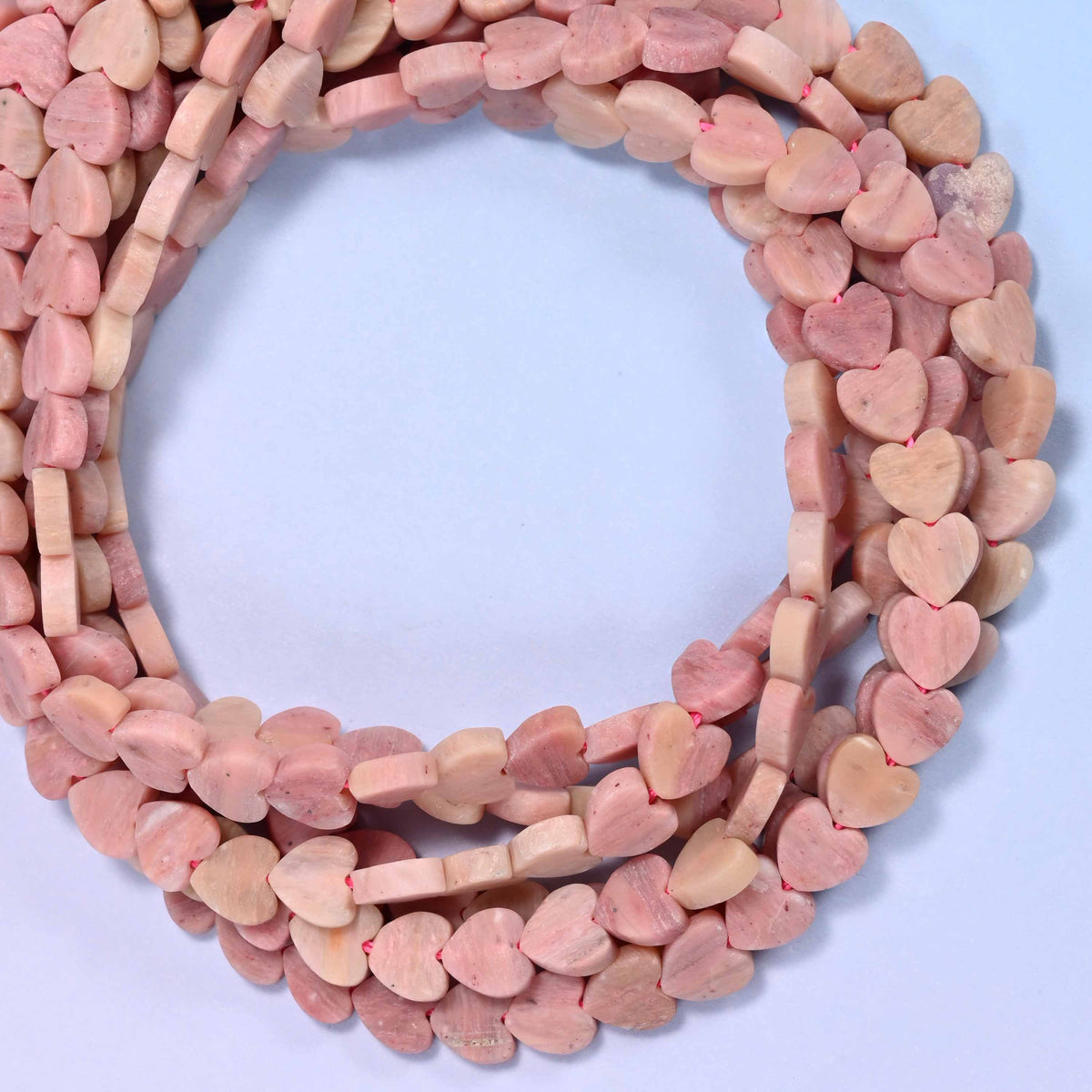Matte Pink Rhodonite flat heart beads, close view of the coiled strands in dusty pink and tan with a matte finish