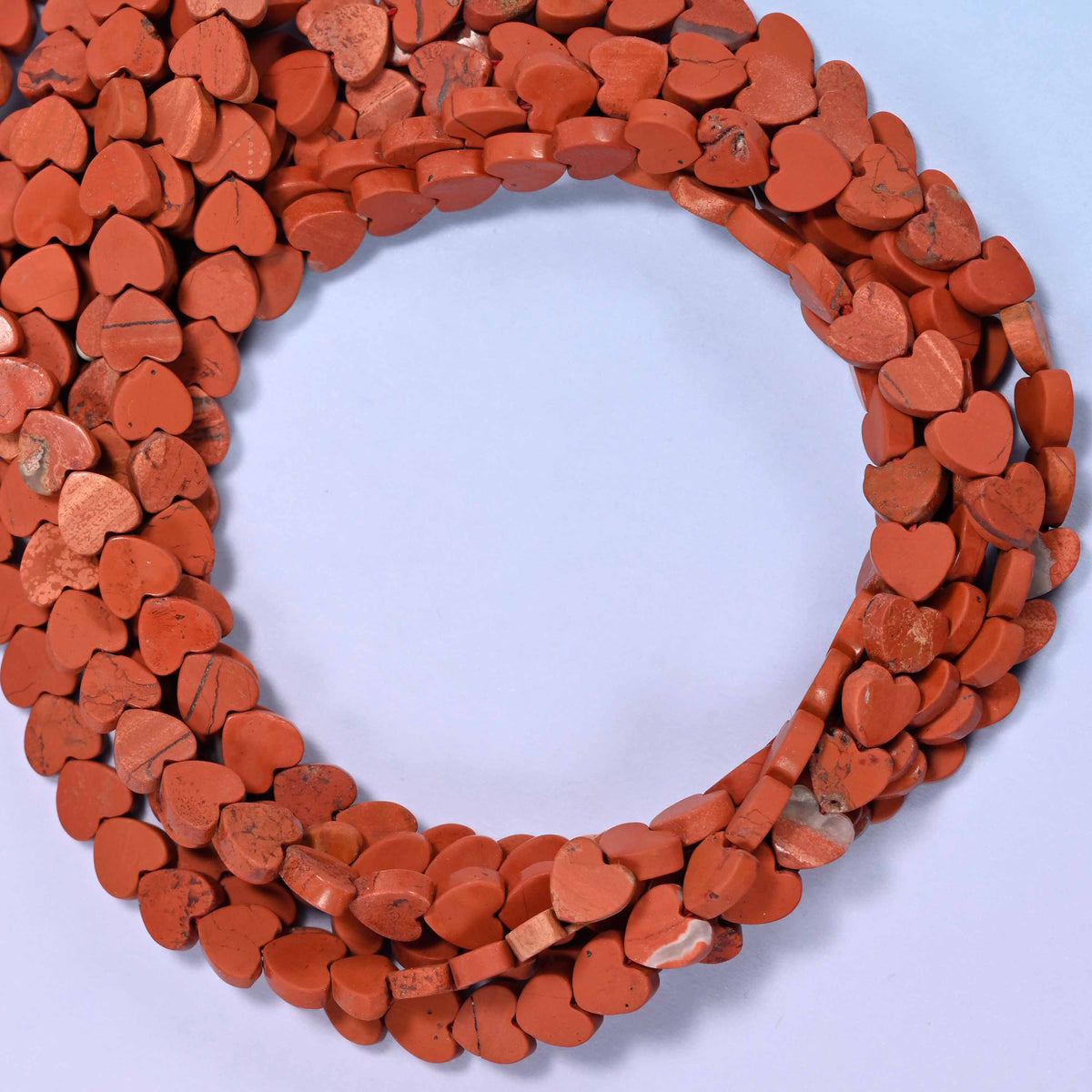 Matte Red Jasper flat heart beads, close view of the coiled strands in brick red with a matte finish