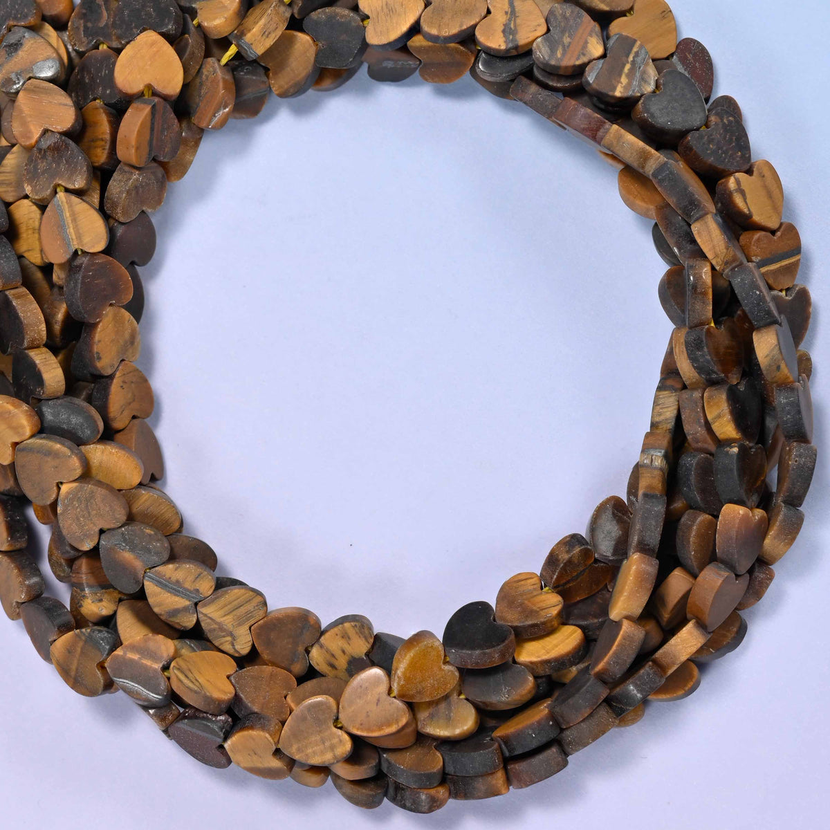 Matte Tiger Eye flat heart beads, close view of the coiled strands in golden brown with dark banding