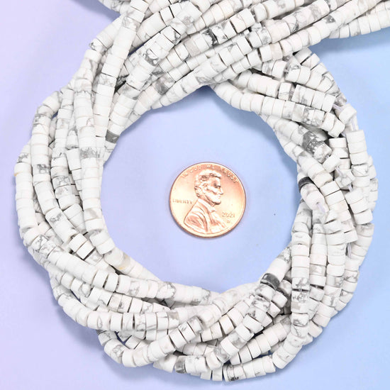 Matte White Howlite heishi disc bead strands coiled around a US penny for size reference