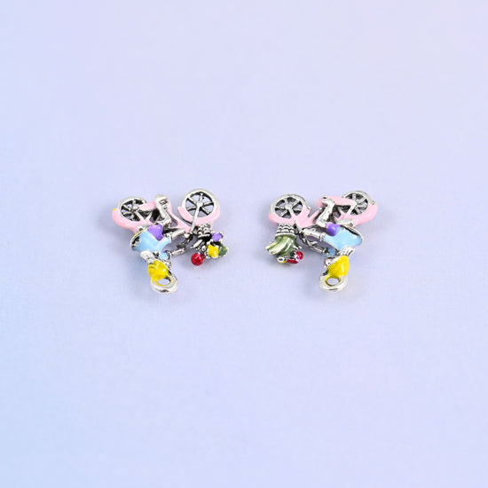 Two bicycle charms lying face down, showing the molded reverse.