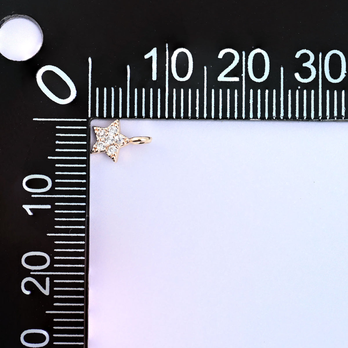 Small gold charms, one star charm measured against a millimetre ruler