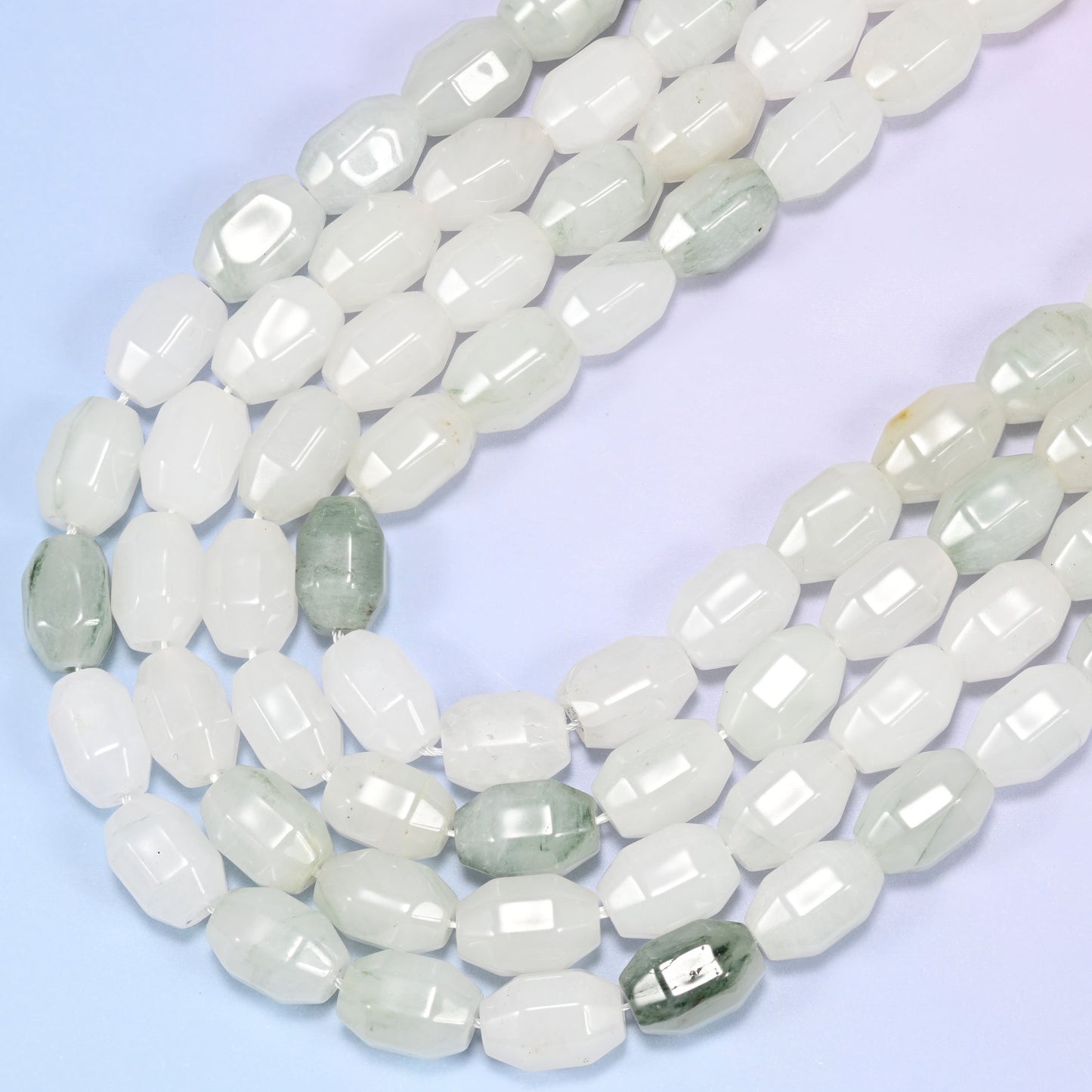 Close-up rows of Tianshan Jade faceted barrel beads from a different angle, showing the white and green color distribution.
