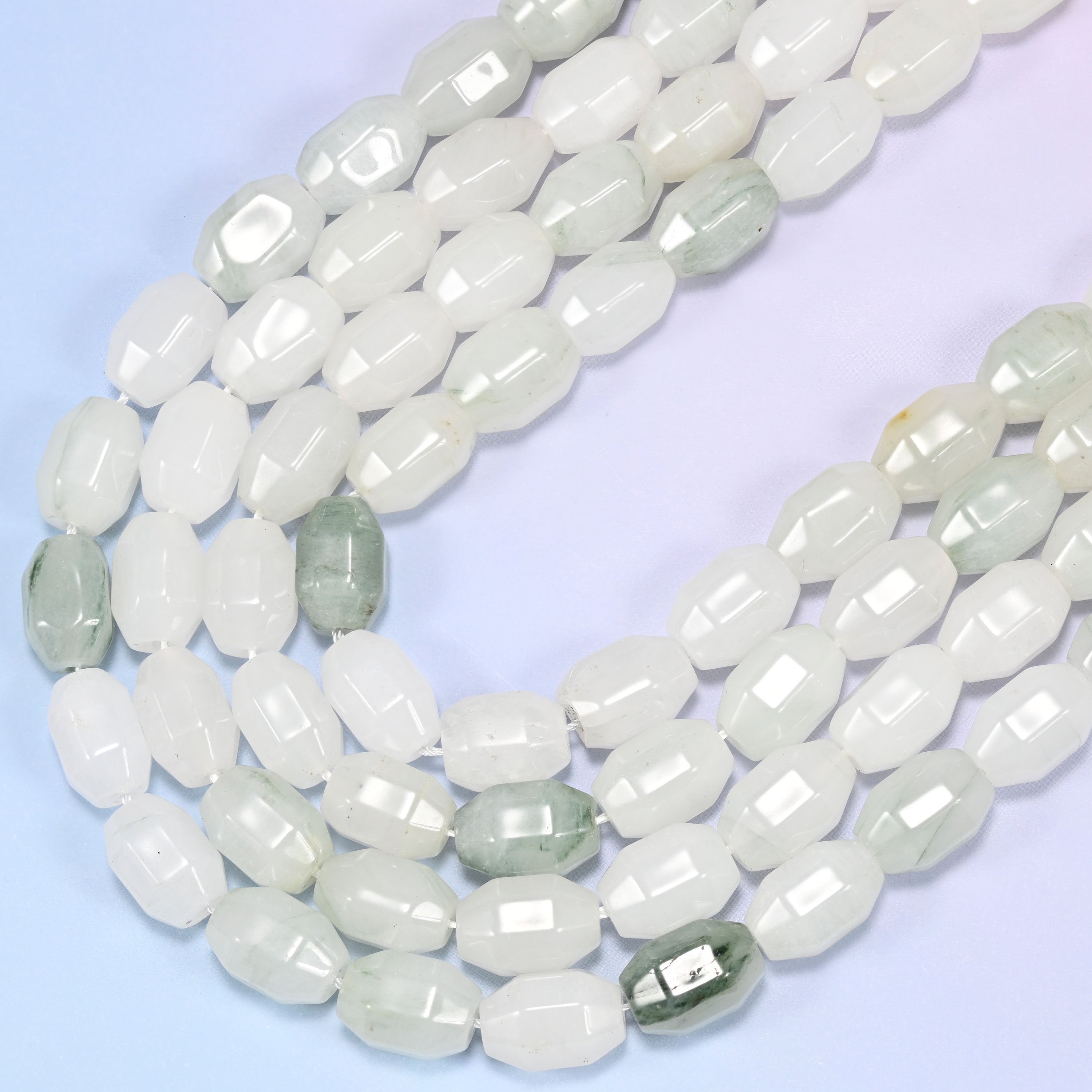 Close-up rows of Tianshan Jade faceted barrel beads from a different angle, showing the white and green color distribution.