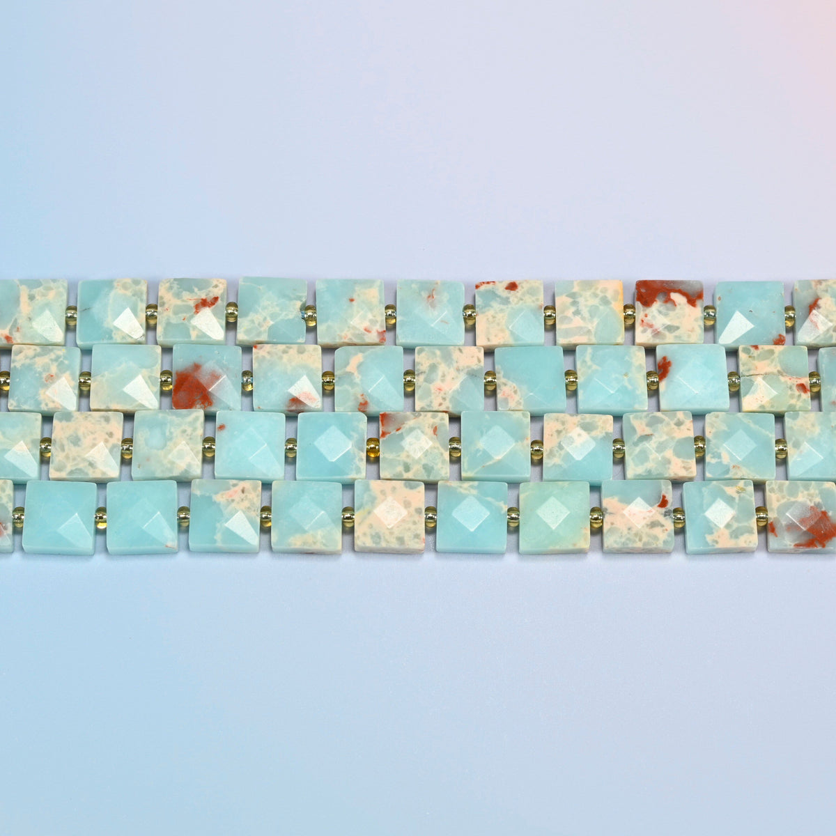 Several strands of dyed blue Shoushan stone faceted flat square beads laid in straight rows