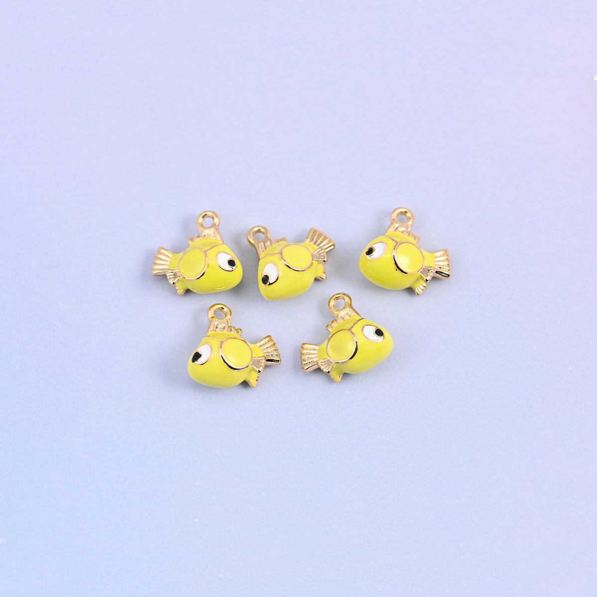 Five fish charms scattered together, yellow green enamel bodies with big cartoon eyes and gold plated fins.