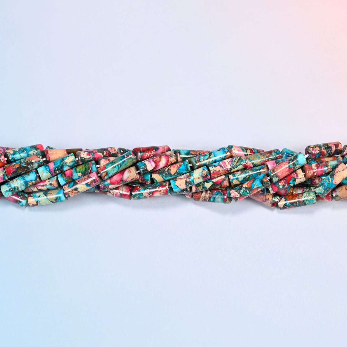 Strands of dyed sea sediment jasper tube beads 13x4mm twisted together in a horizontal row
