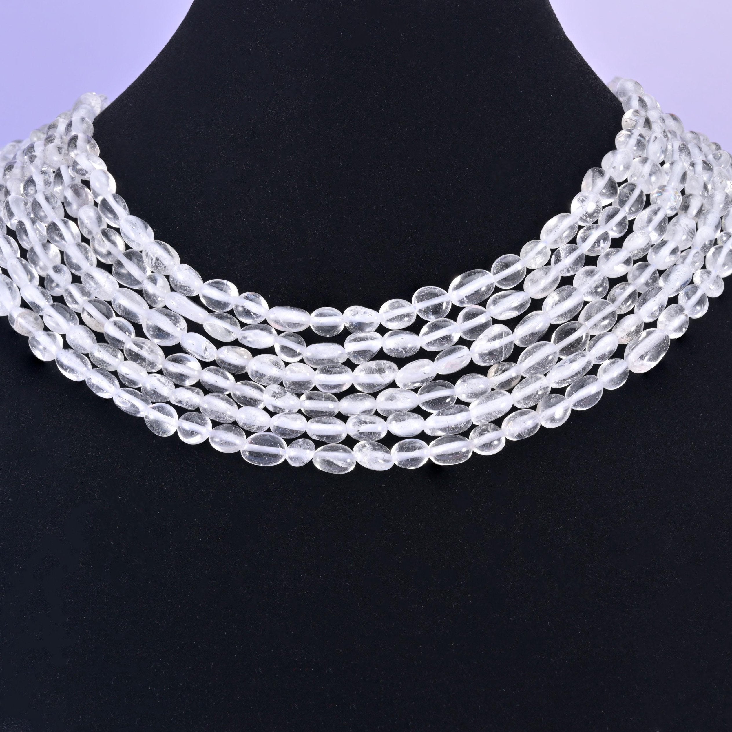 Quartz nuggets on a black display bust, transparent beads standing out against the dark backdrop