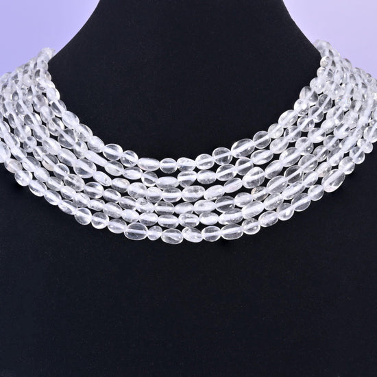 Quartz nuggets on a black display bust, transparent beads standing out against the dark backdrop