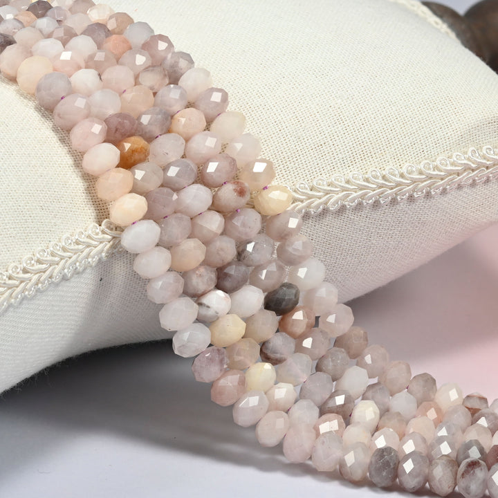 Lavender quartz faceted rondelle beads 5x8mm in soft lilac, cream and blush peach, several strands draped over a white cushion