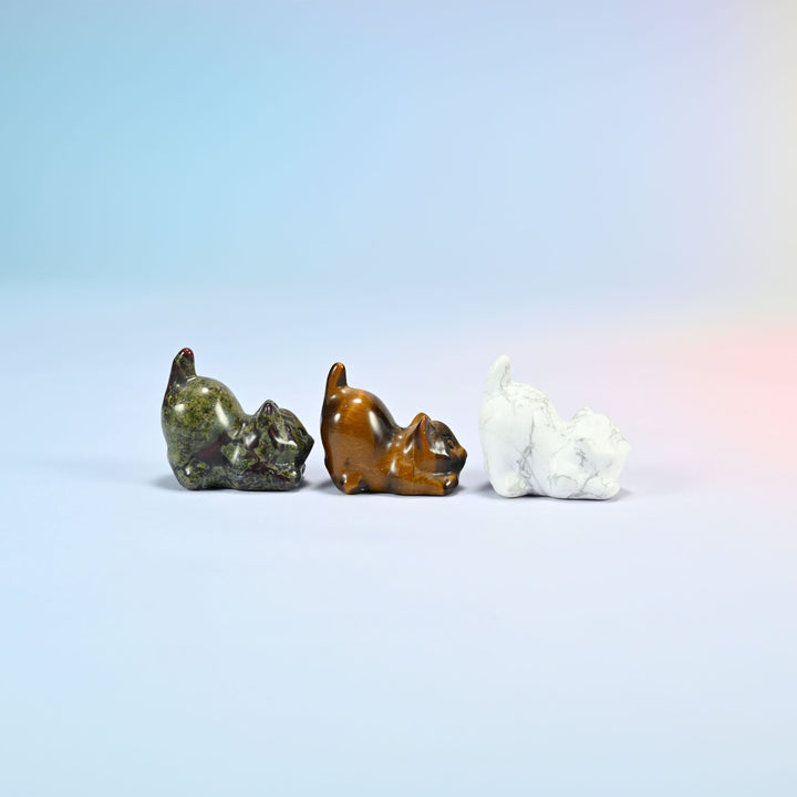 Side view of natural dragon bloodstone, tiger eye and white howlite yoga cat carvings crouched low with their tails curled up