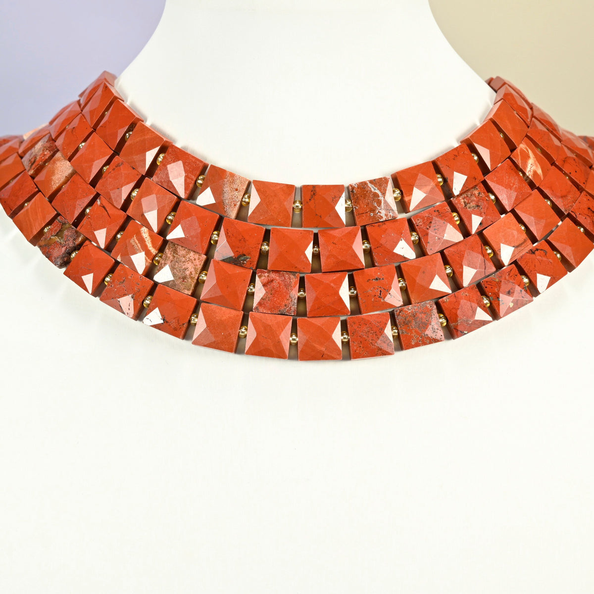 Natural flower red jasper faceted flat square strands arranged as a layered collar on a white display bust, brick red beads across the neck