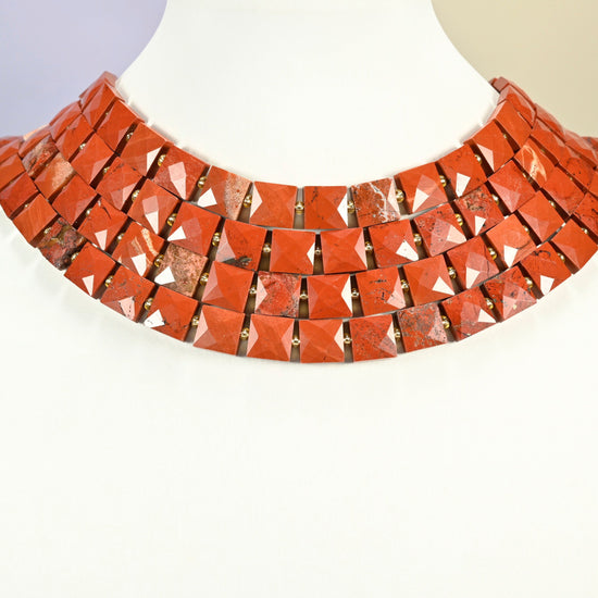 Natural flower red jasper faceted flat square strands arranged as a layered collar on a white display bust, brick red beads across the neck