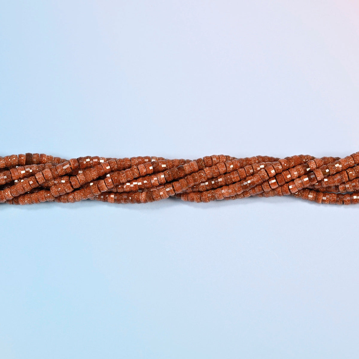 Strands of gold sandstone faceted heishi disc beads twisted together in a horizontal row