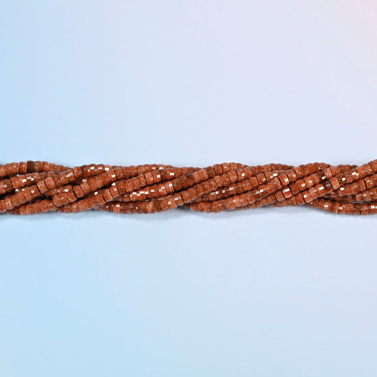 Strands of gold sandstone faceted heishi disc beads twisted together in a horizontal row