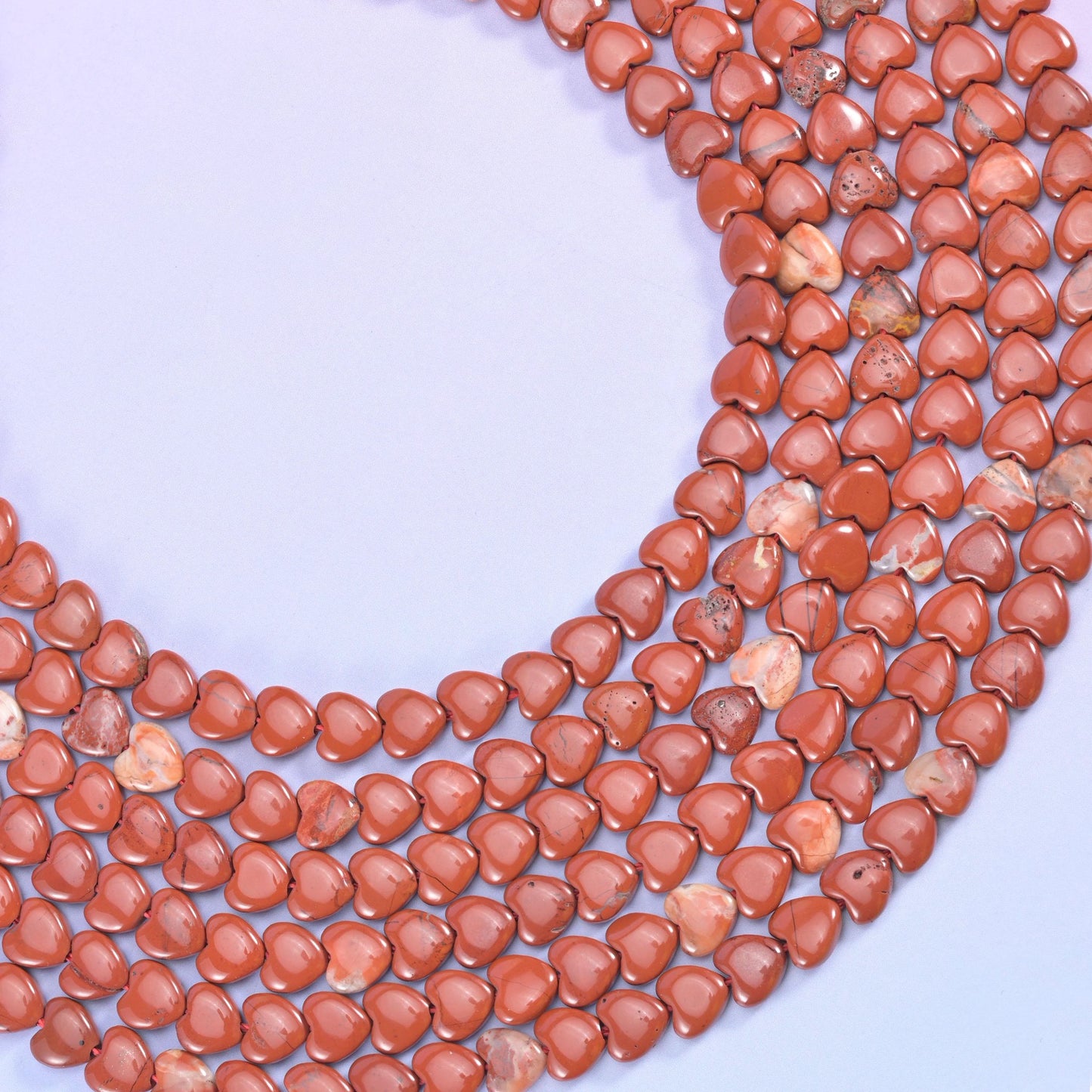 Deep brick red and fully opaque, small flat hearts with a soft satin polish, mostly even terracotta with pale cream patches