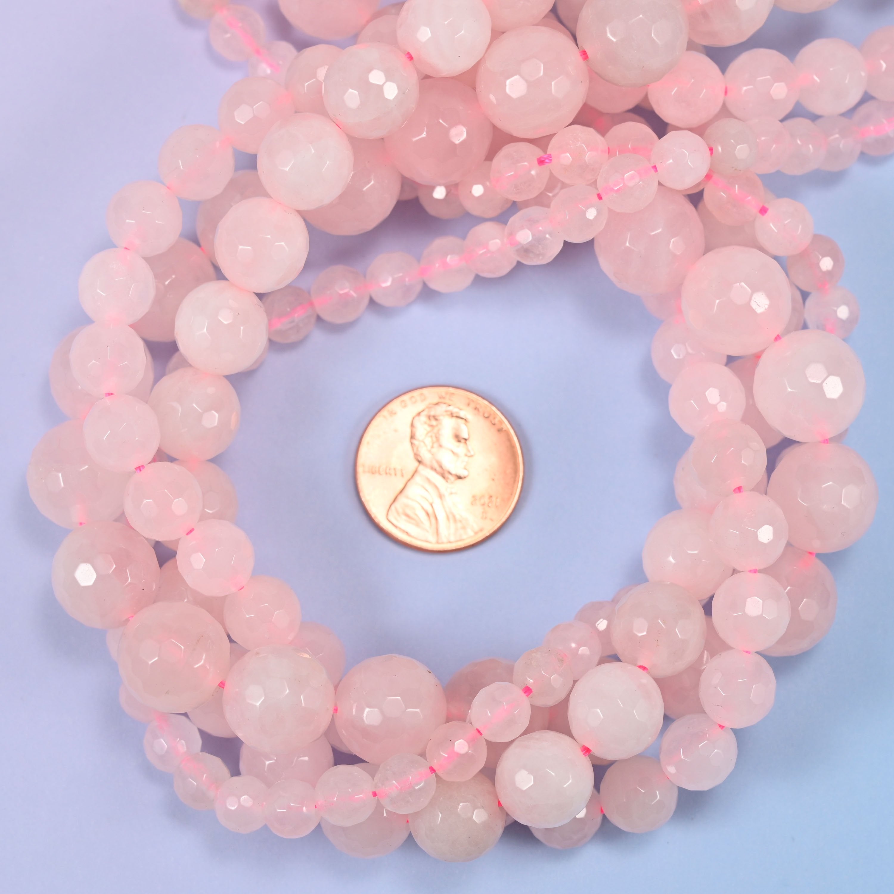 Close-up of pink rose quartz round beads, showing the faceted finish and natural pink tone.