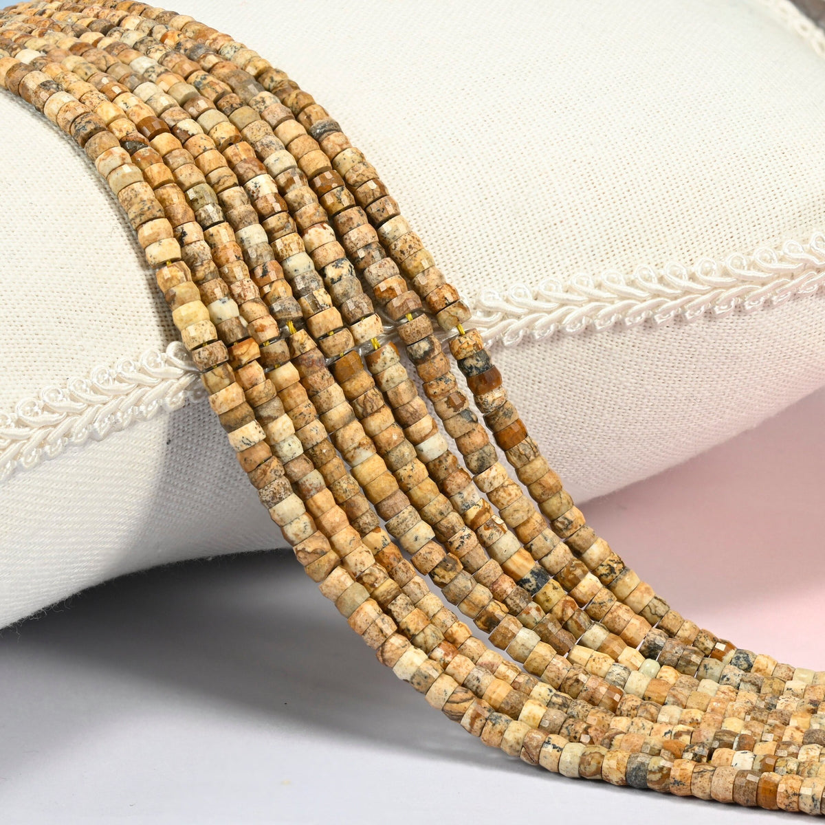 Picture jasper faceted heishi disc beads 2x4mm, several strands draped over a white cushion