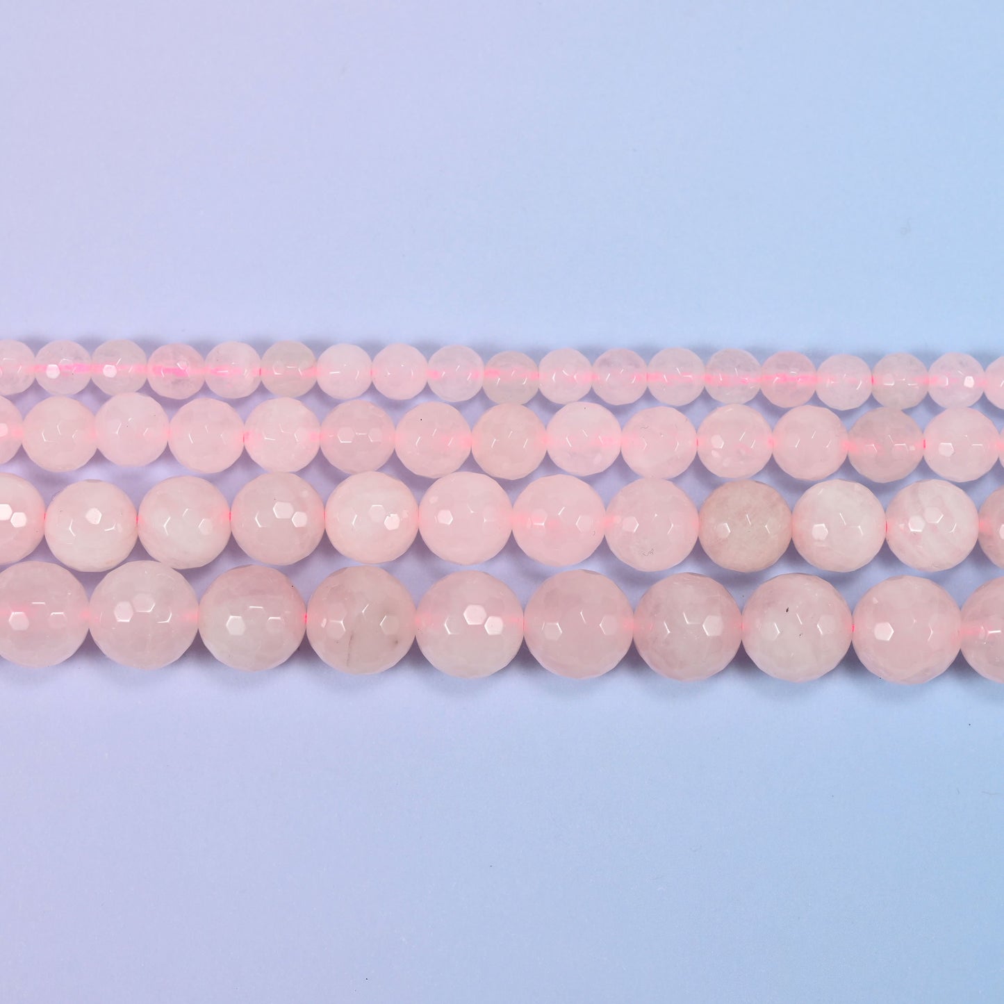 Full 15-inch strand of pink rose quartz round beads laid out for jewelry making.