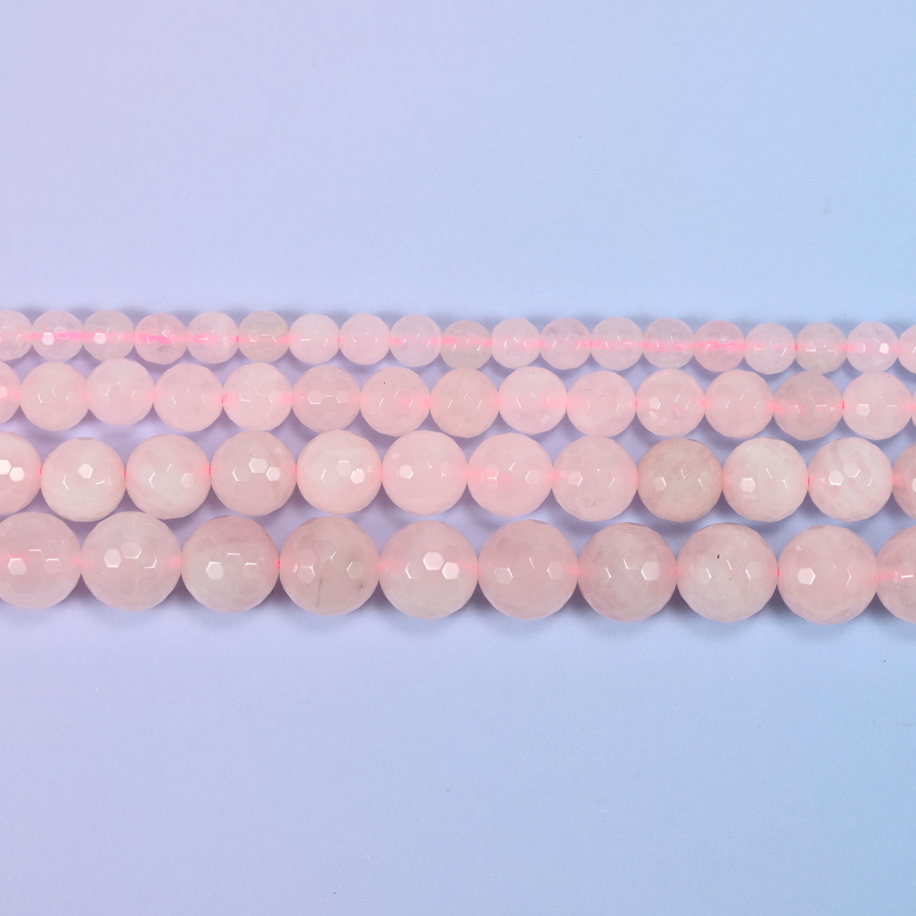Full 15-inch strand of pink rose quartz round beads laid out for jewelry making.