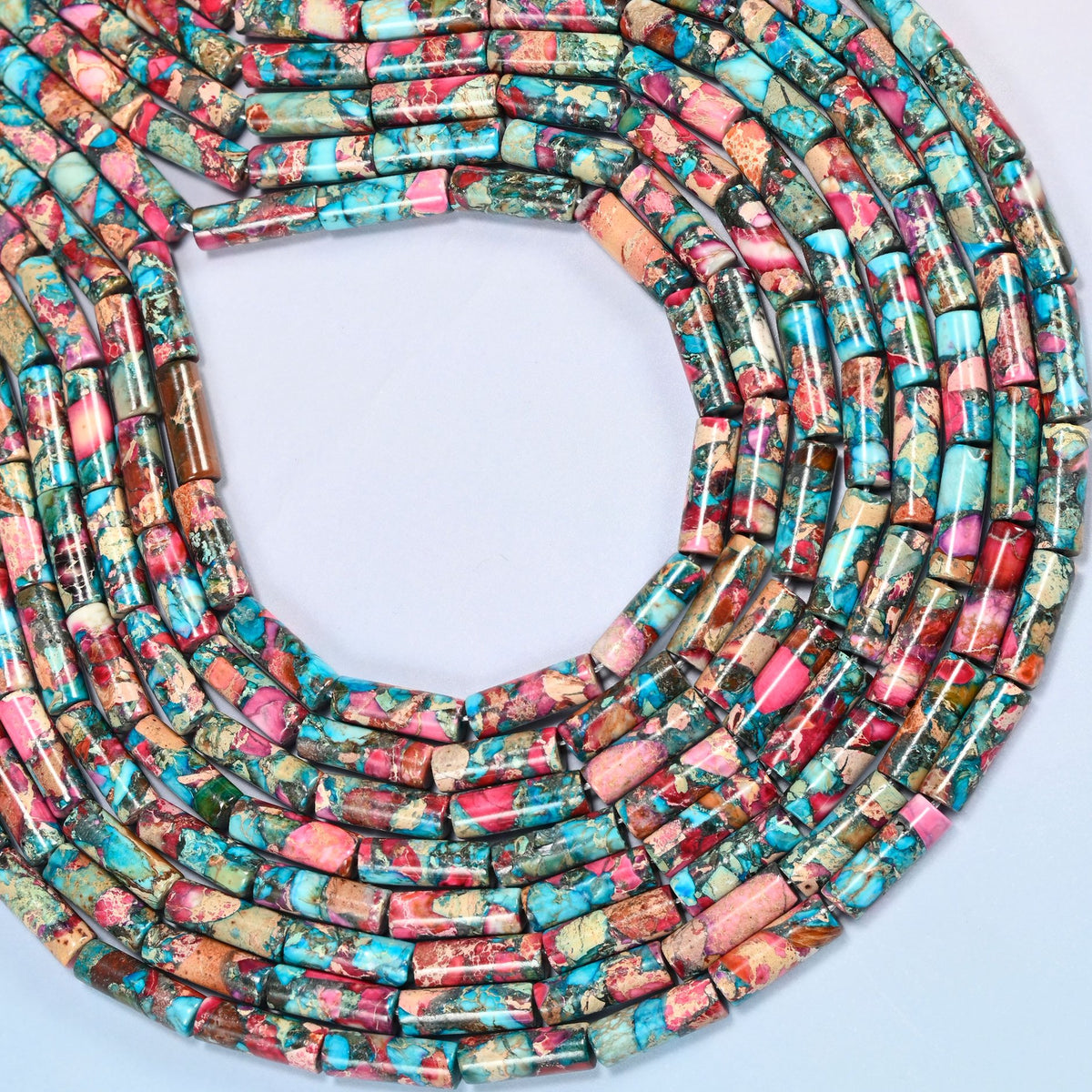 Dyed sea sediment jasper tube beads 13x4mm curved into an open loop, showing the turquoise and pink mix across whole strands