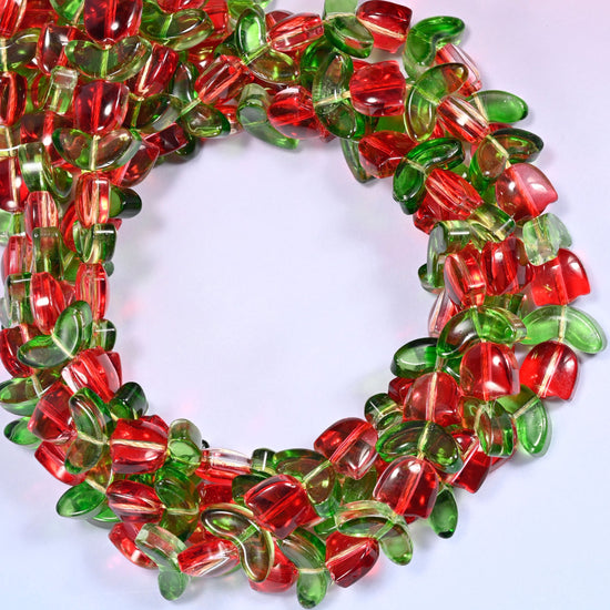 Horizontal row of red tulip and green leaf glass beads laid straight across a lavender and pink gradient background.