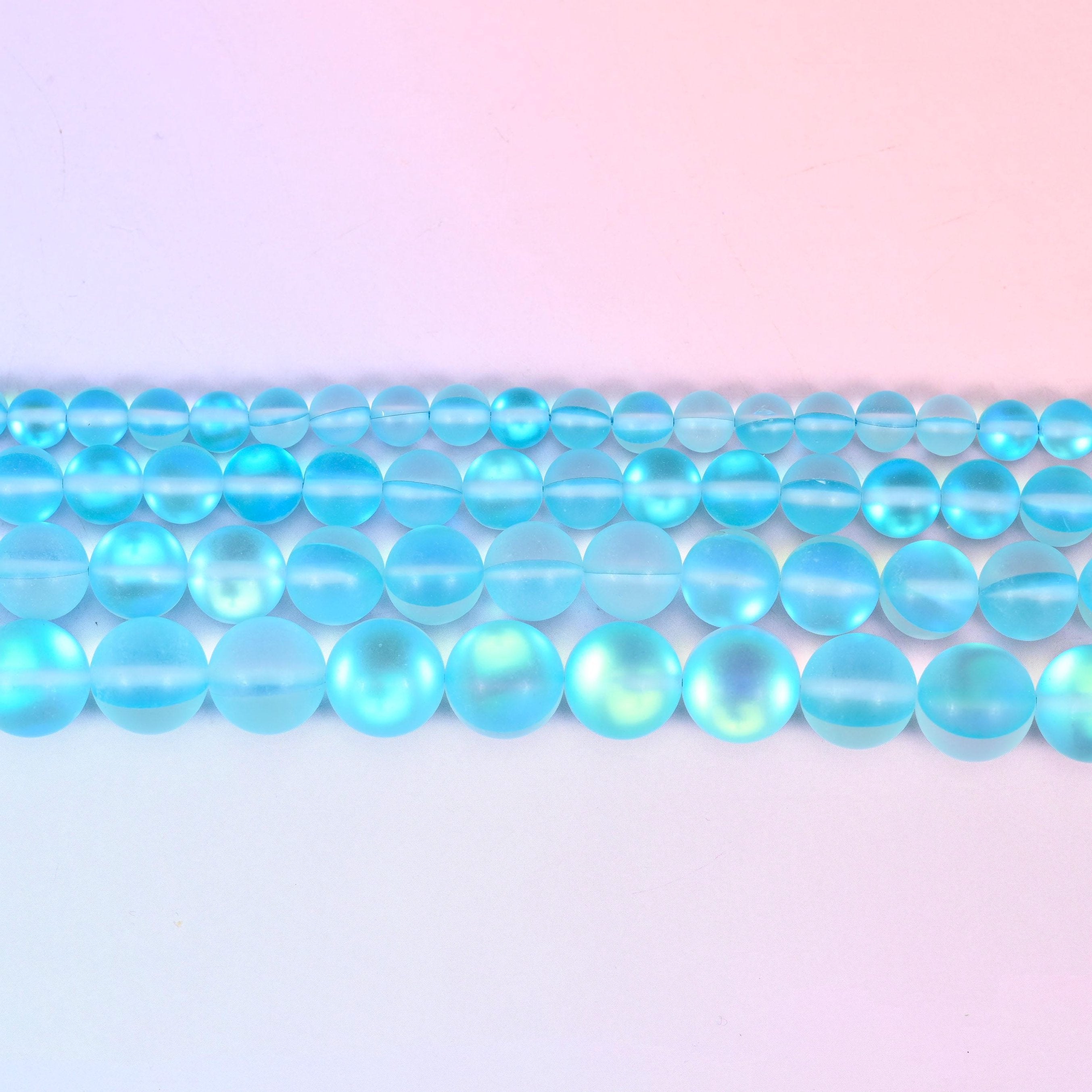 Matte glass beads in bright aqua with a green-and-gold aurora glow
