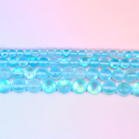 Matte glass beads in bright aqua with a green-and-gold aurora glow