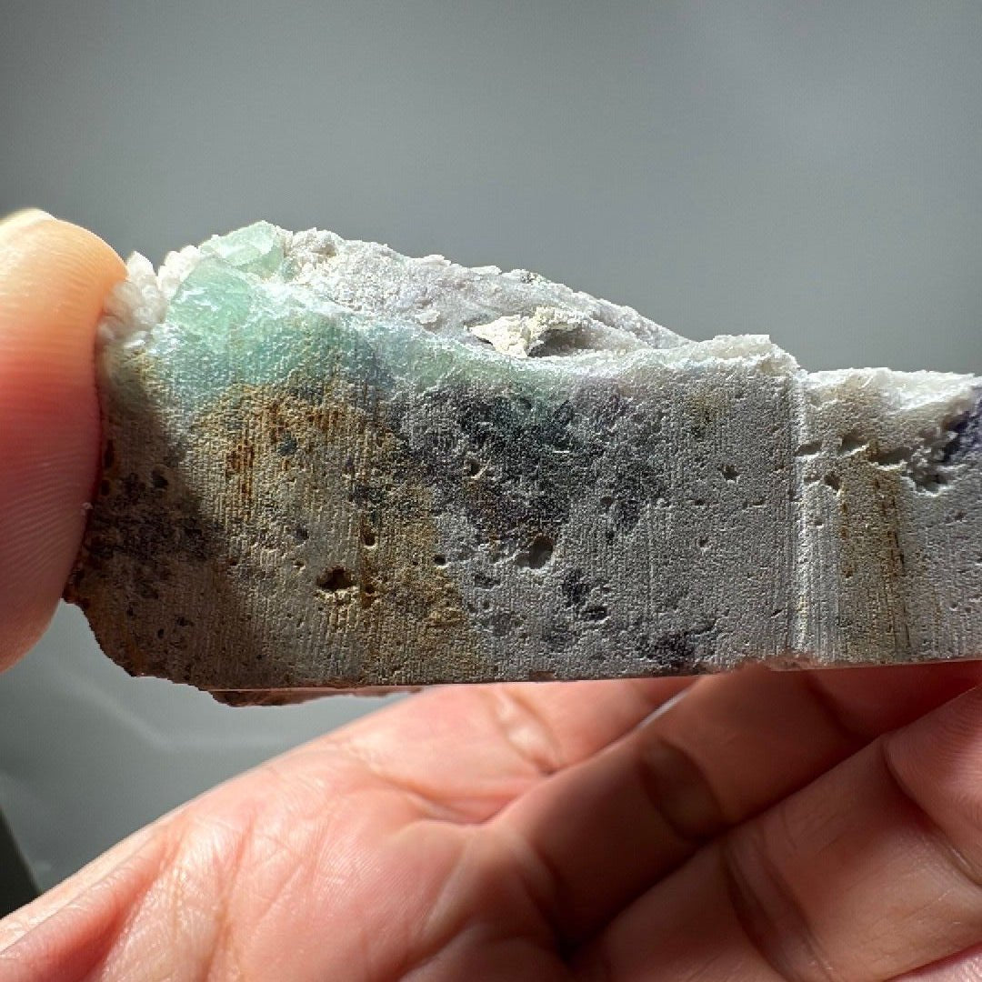 Side profile of the specimen showing the flat grey base beneath the crystal-covered top
