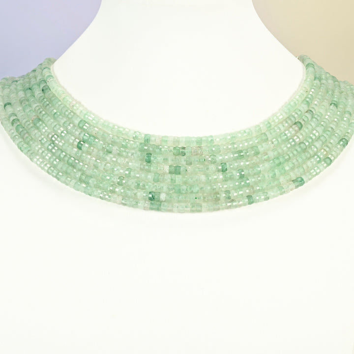 Green strawberry quartz faceted heishi disc strands arranged as a layered collar on a white display bust, light green beads across the neck