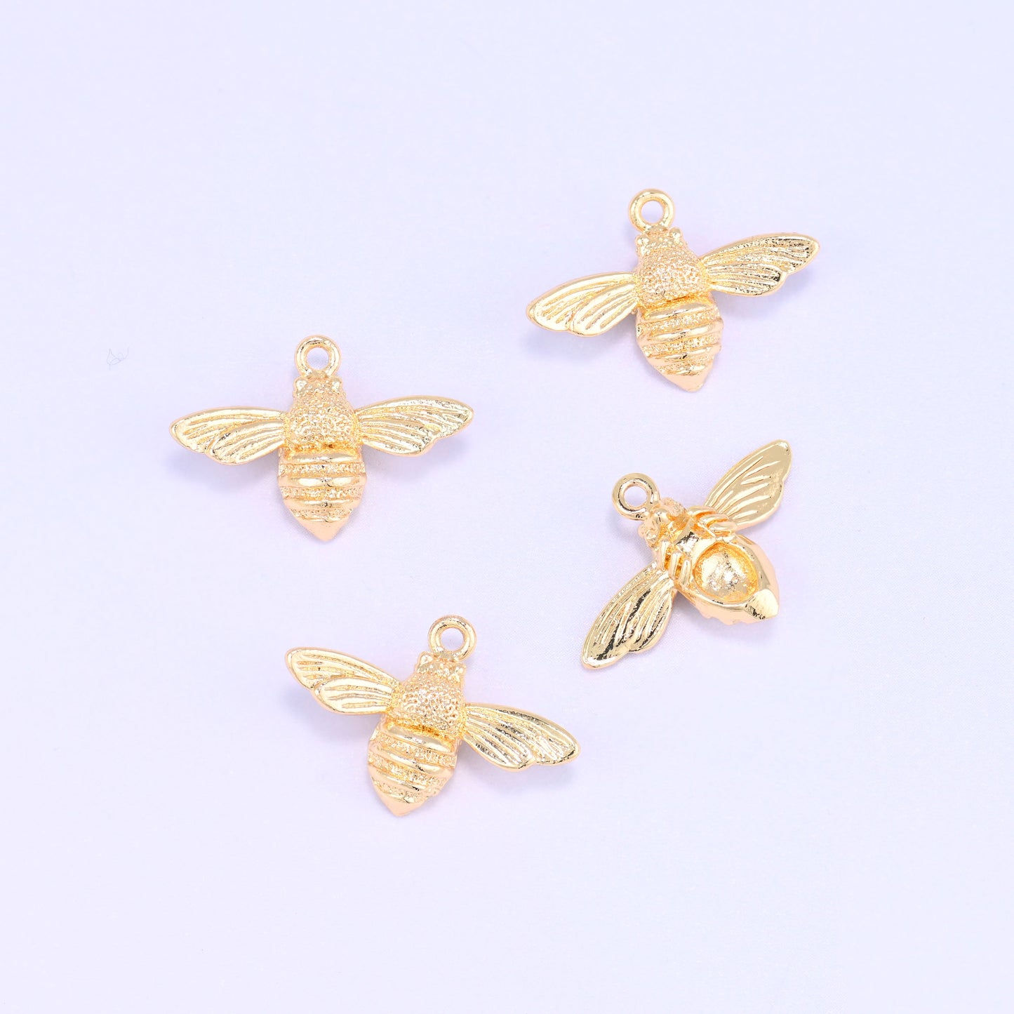 Small gold charms bee, five 18K gold plated charms scattered to show the shape and polished finish