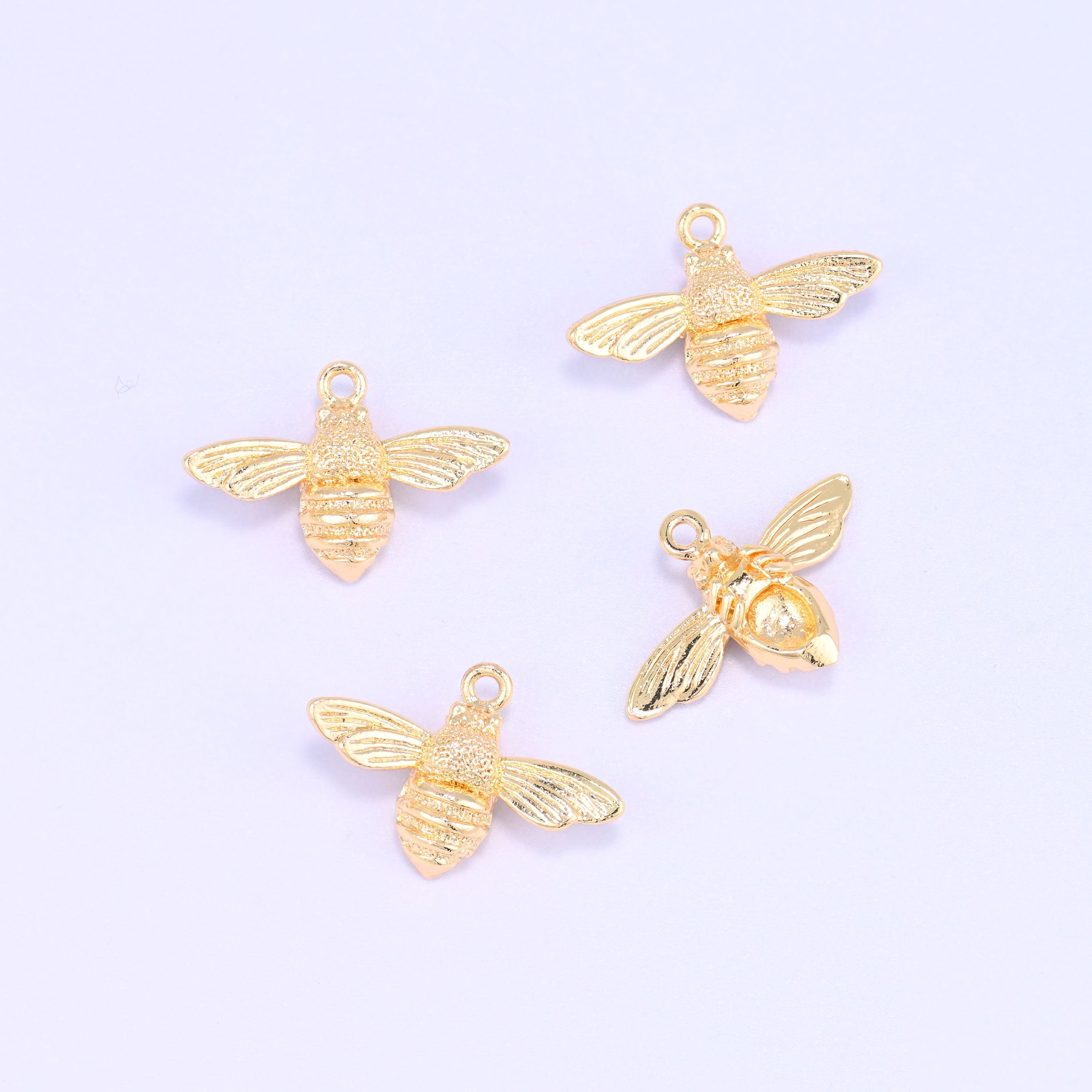 Small gold charms bee, five 18K gold plated charms scattered to show the shape and polished finish
