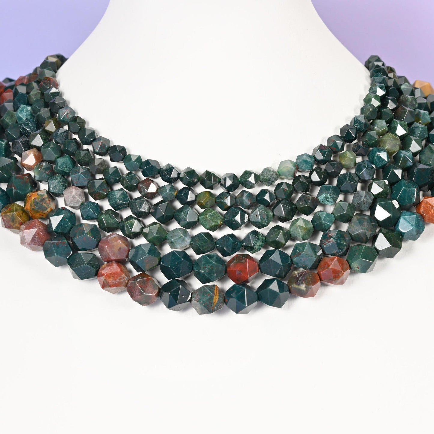 Indian Bloodstone star cut beads looped around a white neck form, several strands sitting together as a collar