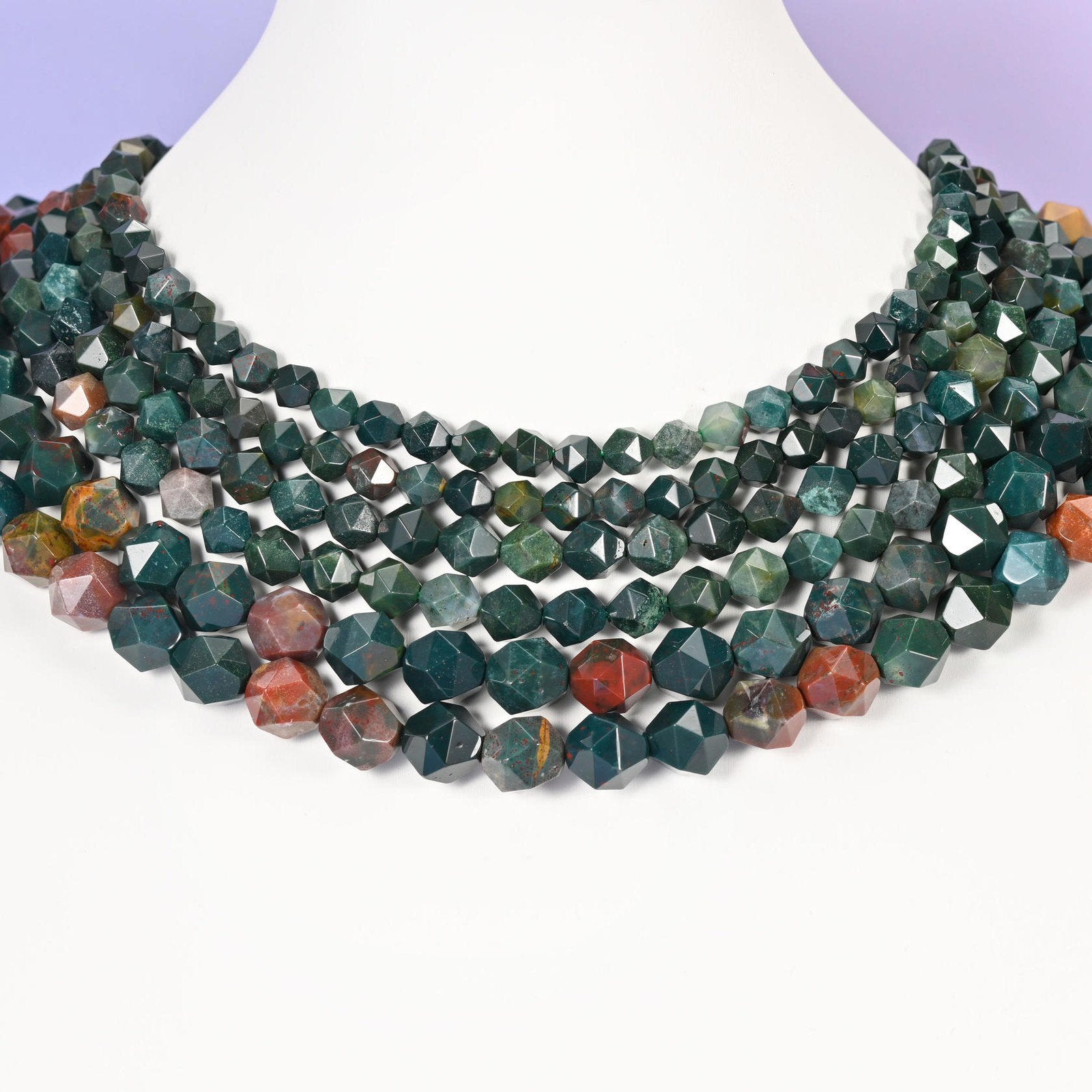 Indian Bloodstone star cut beads looped around a white neck form, several strands sitting together as a collar