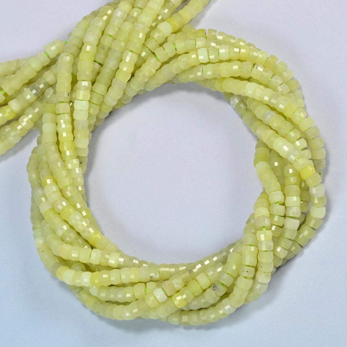 Lemon Jade faceted heishi disc beads coiled into overlapping loops, whole strands of soft lemon yellow-green stone