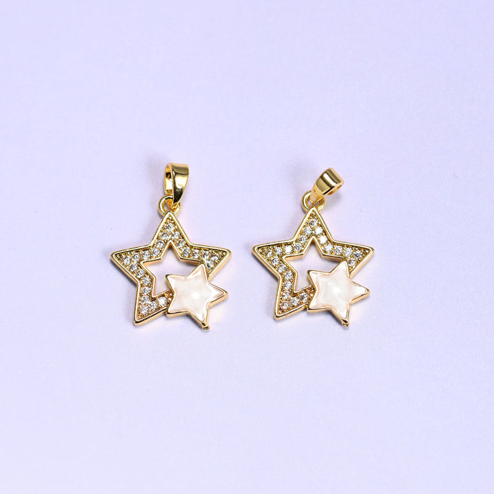 Double Stars Zirconia Charms in gold and white, two 18K gold plated pendants with clear zirconia pave outer stars and cream shell inner stars, shown side by side on a lilac background.
