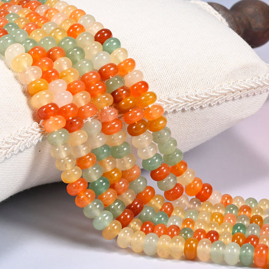 Gold Silk Jade gemstone rondelle beads draped in rows over a cushion, orange cream and light green discs on 15.5 inch strands