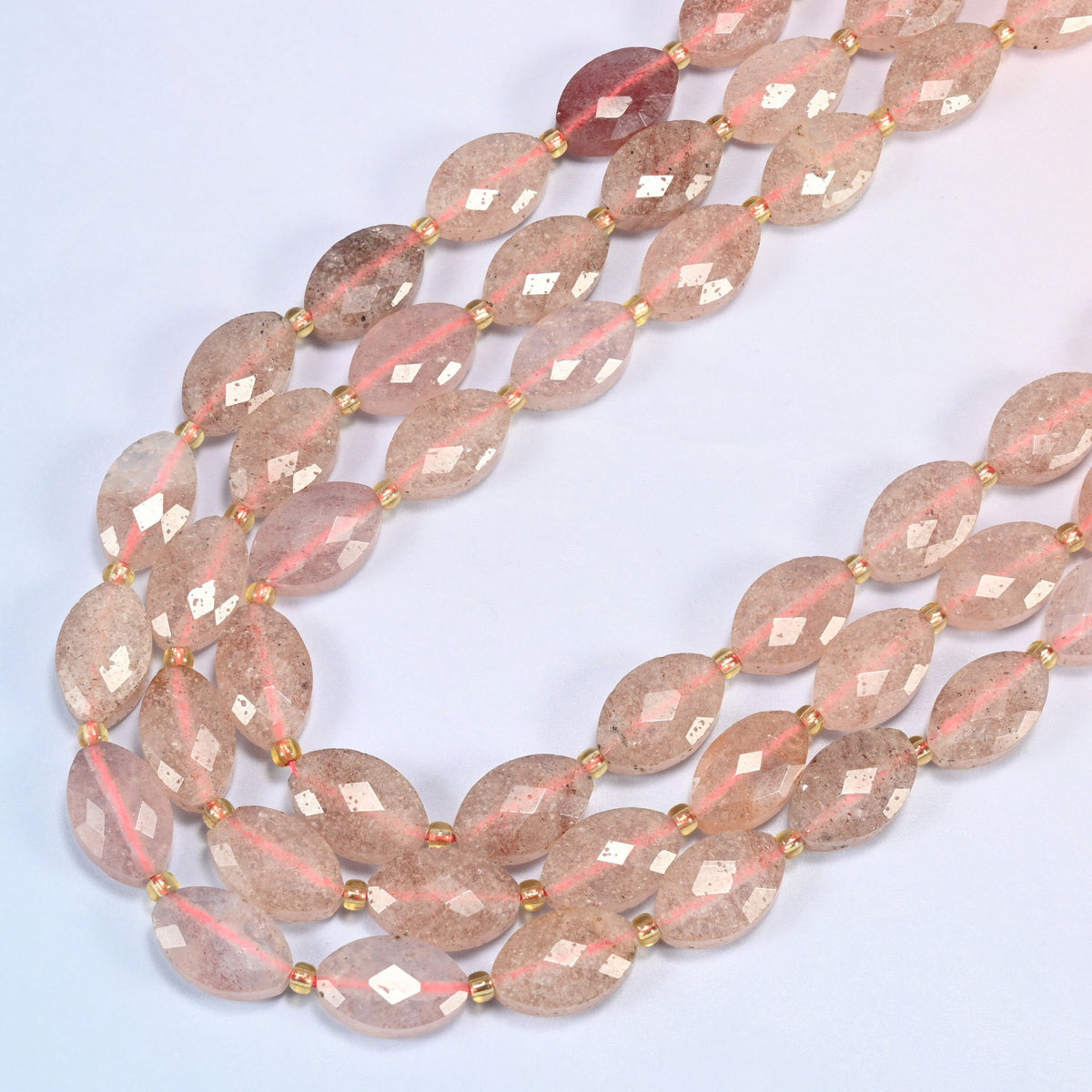 Strawberry quartz faceted flat oval beads in several strands curved into a wide U, soft pink stone with fine red flecks