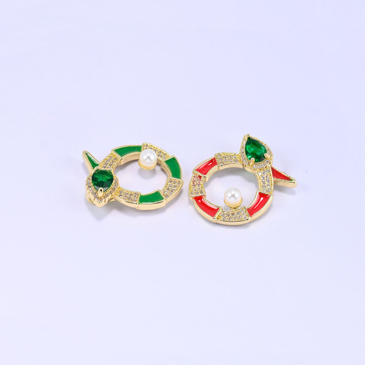 Green and red round snake charms angled together, showing how the enamel colour changes the look while the pearl and green stone stay the same.