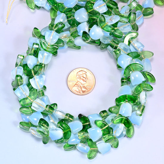 Loose circular coil of tulip and leaf glass bead strands on a lavender background with a penny in the center for size comparison.