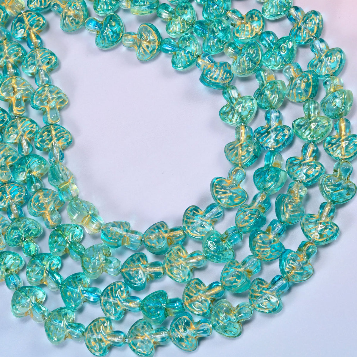 Aqua gold flat mushroom glass beads looped into one wide open ring, the strands running off both sides of the frame.