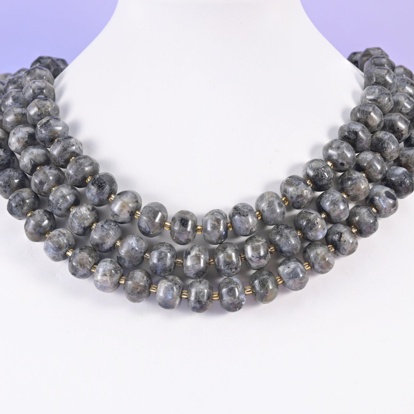 Multi-strand pumpkin rondelle necklace on a white display bust, grooved charcoal beads at the collarbone