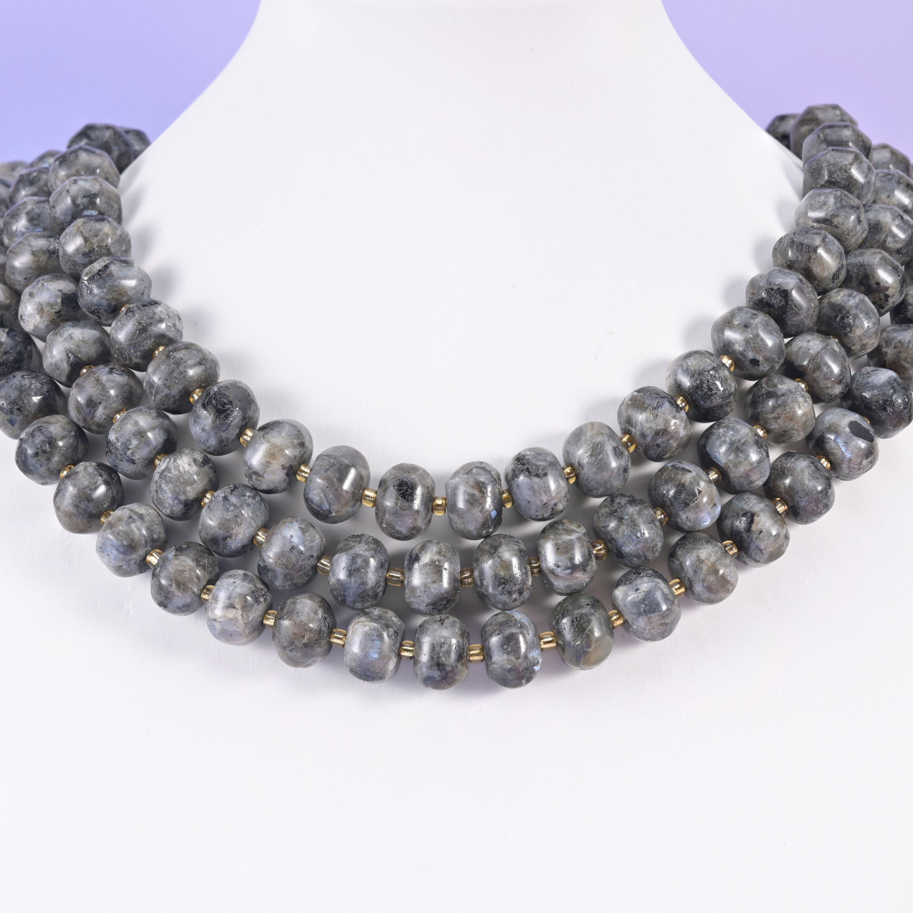 Multi-strand pumpkin rondelle necklace on a white display bust, grooved charcoal beads at the collarbone