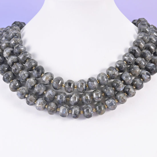 Multi-strand pumpkin rondelle necklace on a white display bust, grooved charcoal beads at the collarbone