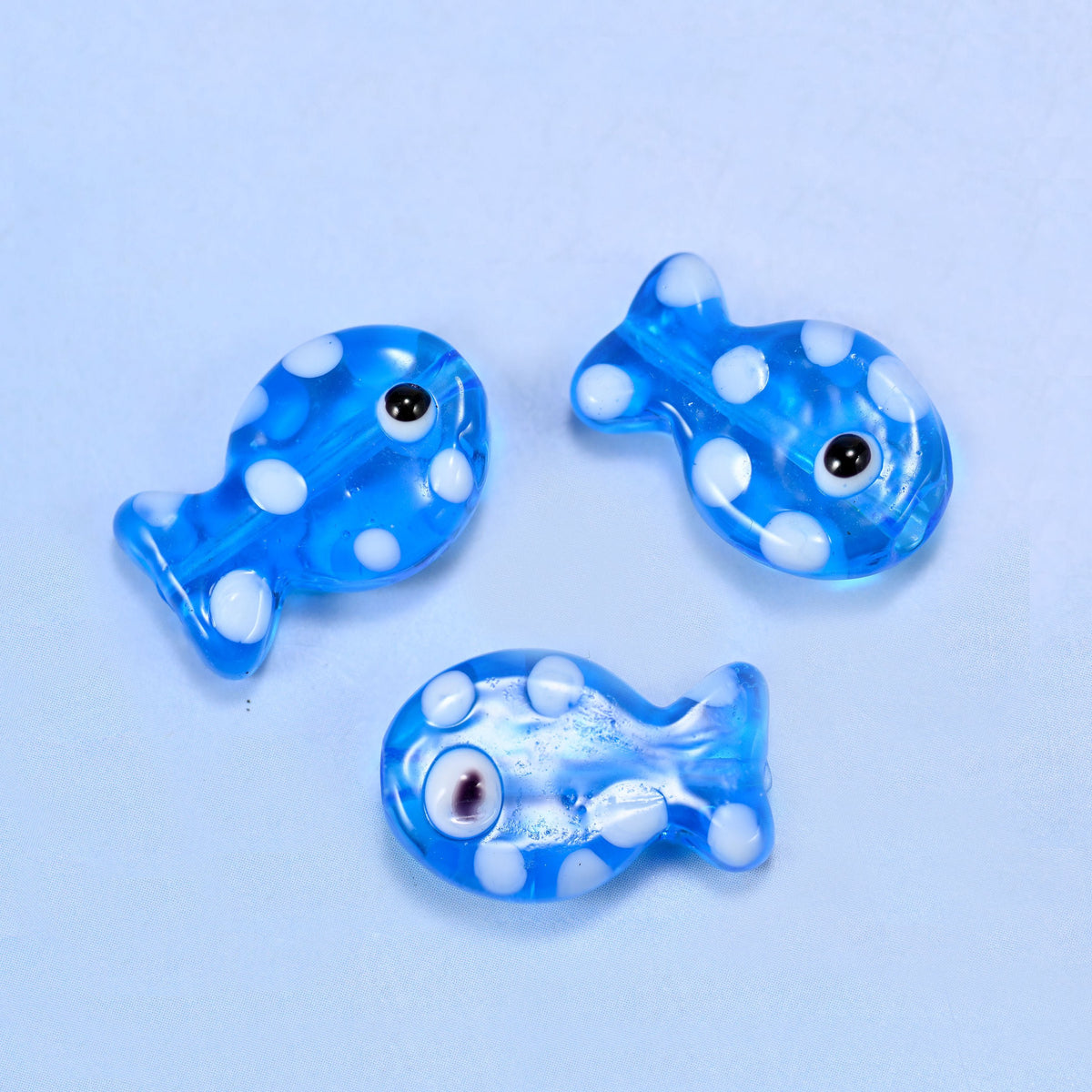 Translucent cornflower blue lampwork fish scattered with opaque white dots and a single black eye