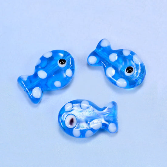 Translucent cornflower blue lampwork fish scattered with opaque white dots and a single black eye