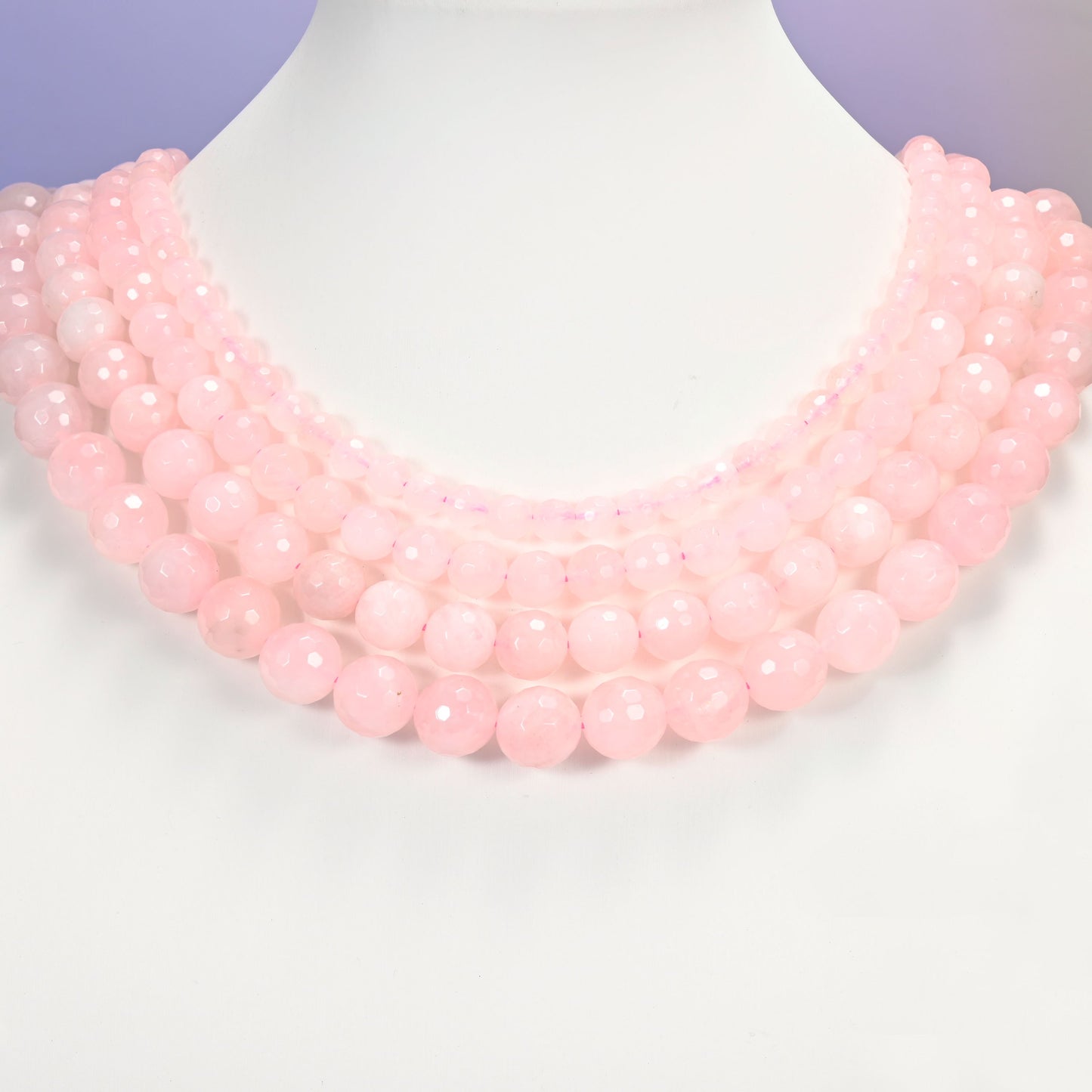 Close-up of pink rose quartz round beads, showing the faceted finish and natural pink tone.