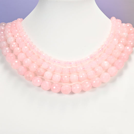 Close-up of pink rose quartz round beads, showing the faceted finish and natural pink tone.
