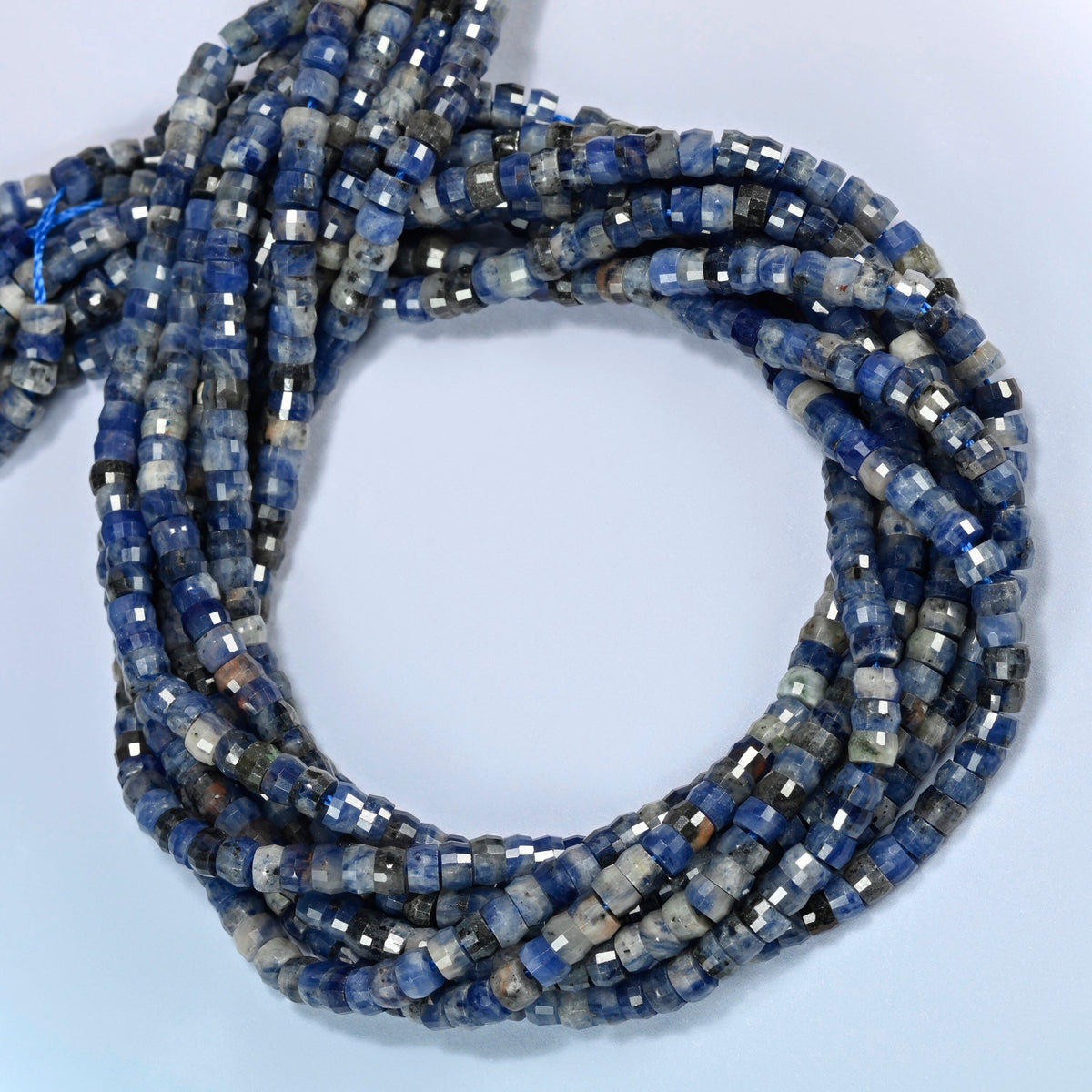 Sodalite faceted heishi disc beads coiled into overlapping loops, whole strands of deep blue and white stone