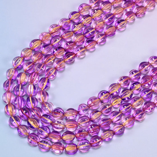 Purple gold pumpkin glass beads, several strands laid in a wide sweeping curve across the frame.